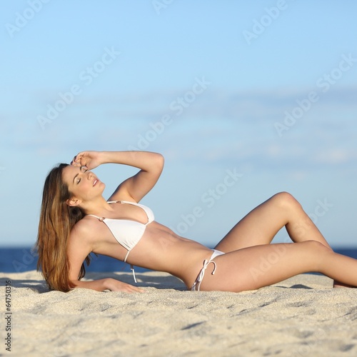 Beautiful fitness woman body sunbathing on the beach
