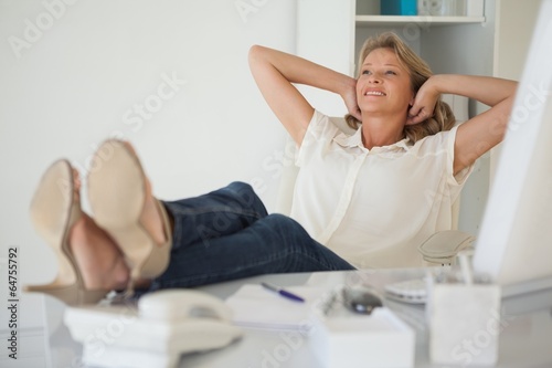 Casual businesswoman sitting at her desk with feet up