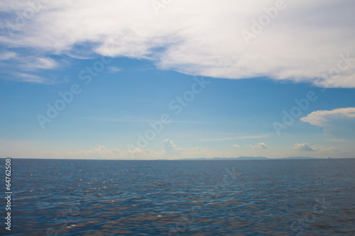 ocean surface and blue sky with clouds with mountain view