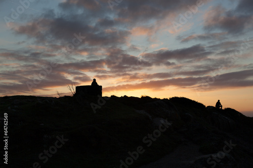 Silhouette of tourists sitting on rocks at sunset, Cote D'Emerau