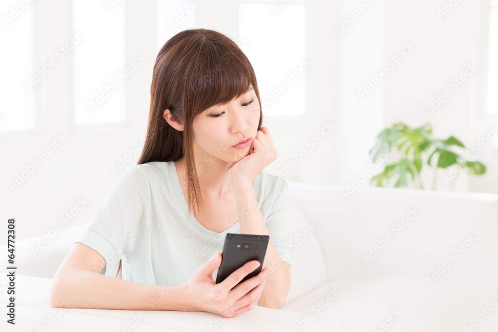 部屋でスマートフォンを見る女性 部屋でスマートフォンを見る女性
