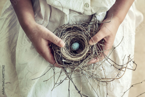 Girl Holding Blue Speckled Egg in Bird Nest on Lap