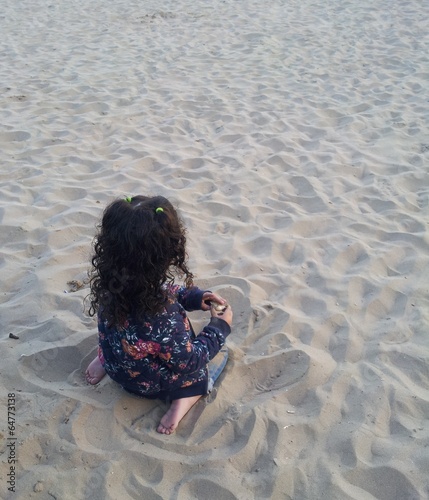 Niña jugando sola en la playa photo