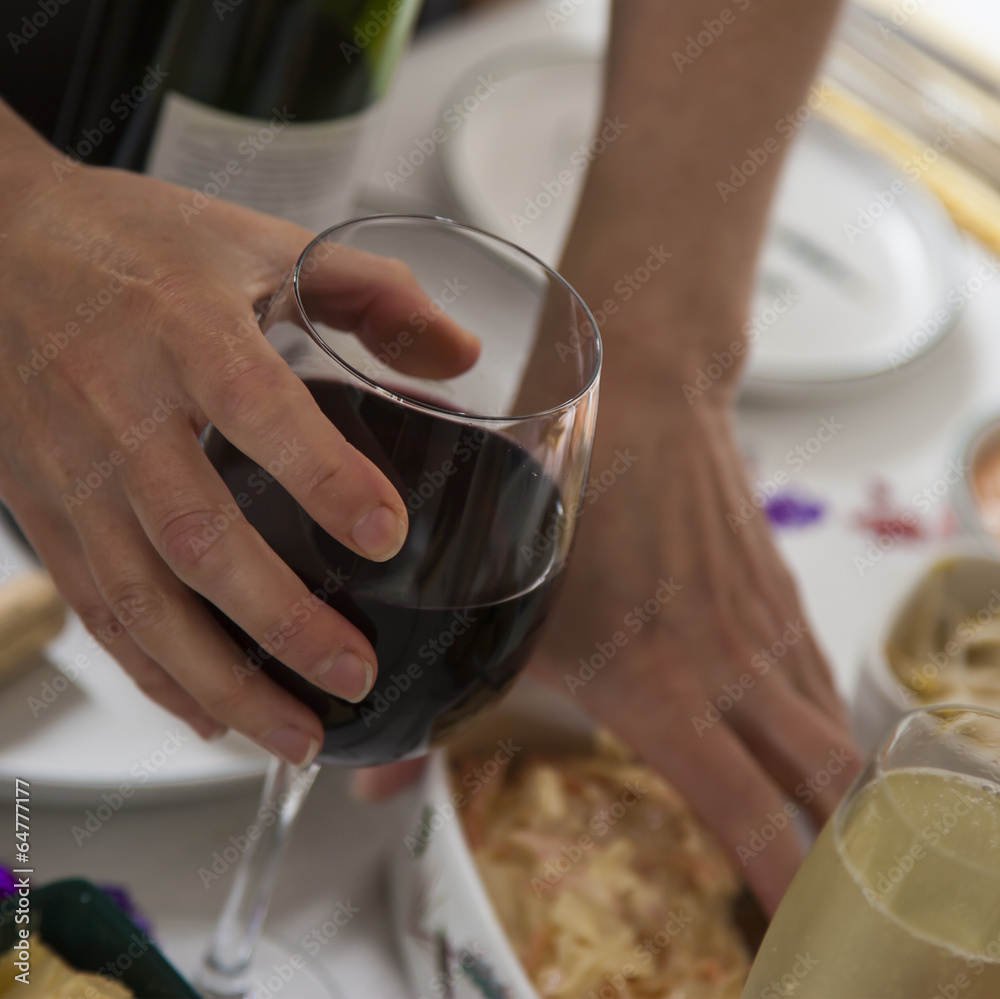 Glass of red wine in womans hand at buffet.