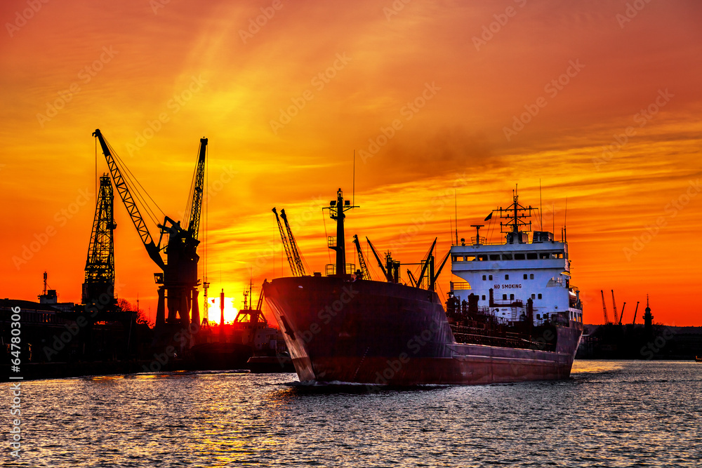 Silhouette of sea port cranes over sunset