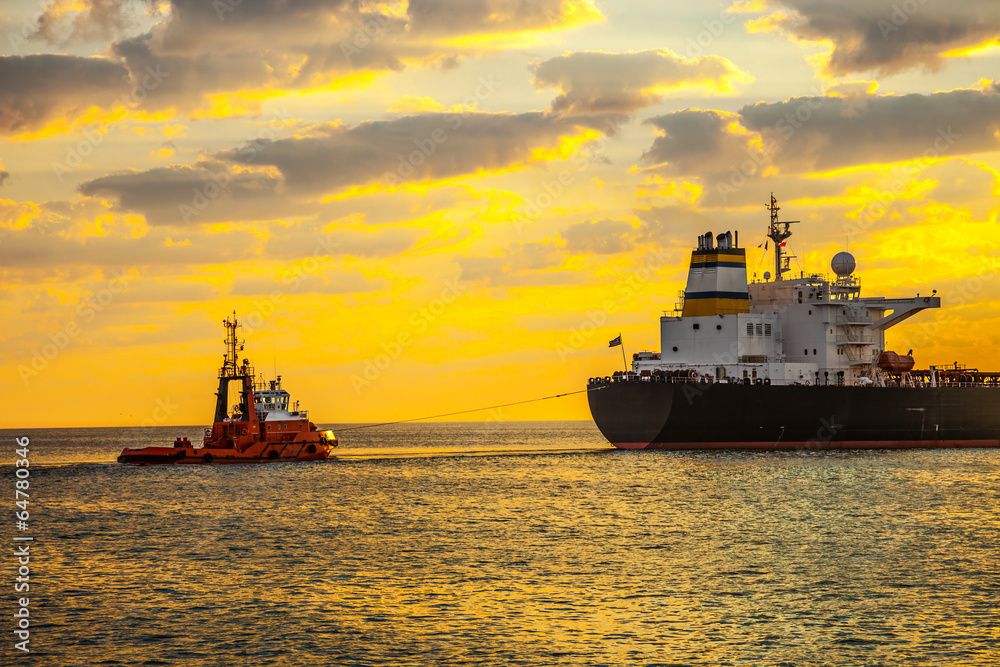 Obraz premium Tug boat pulling the tanker ship at sea.