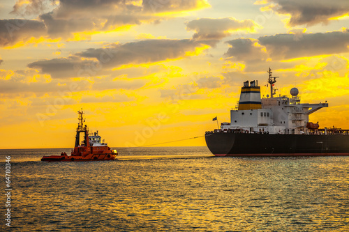 Tug boat pulling the tanker ship at sea.