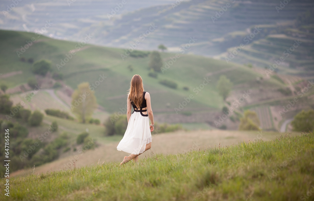 woman in white dress standing on grassy hill