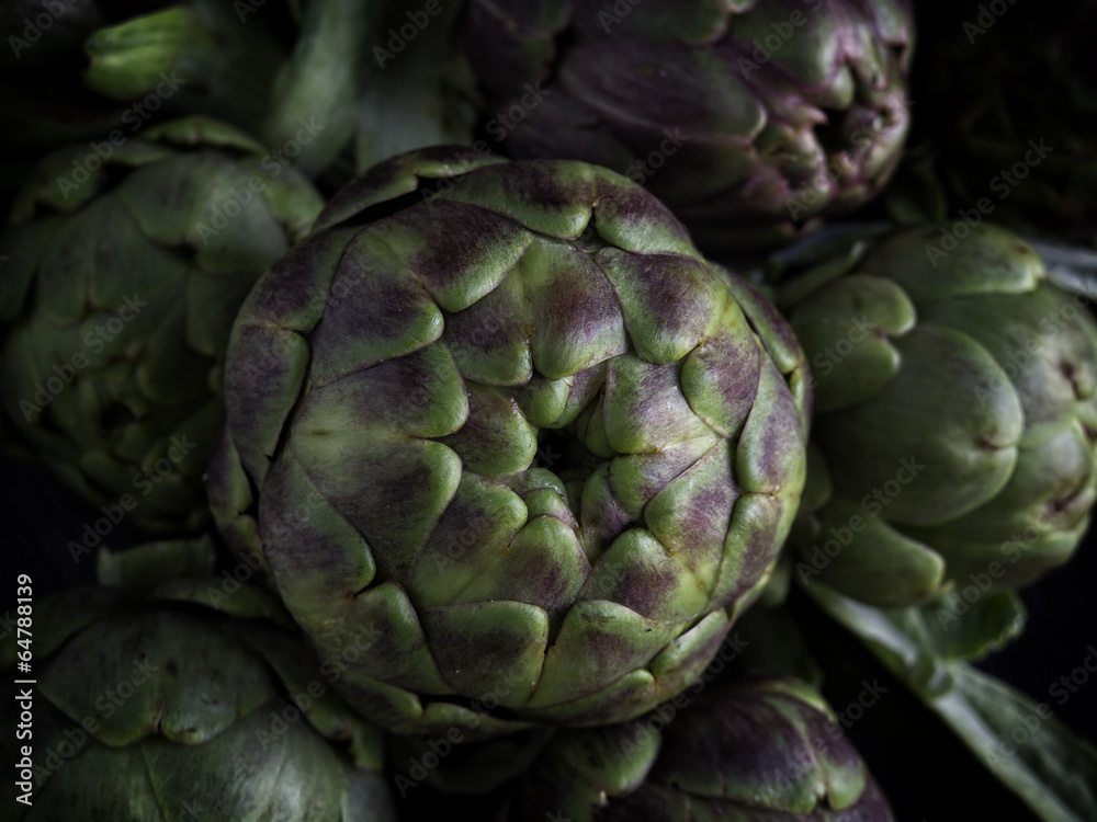 Obraz premium Freschi carciofi romani su sfondo scuro da cucinare