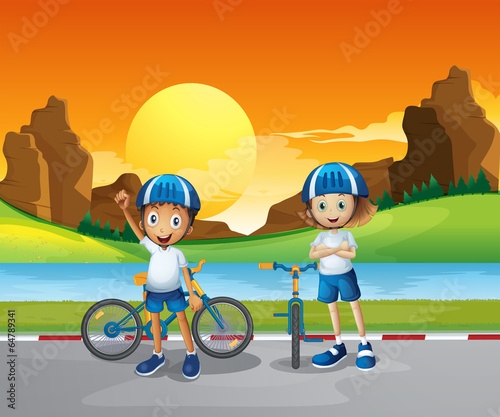Two kids with their bikes standing at the road near the river