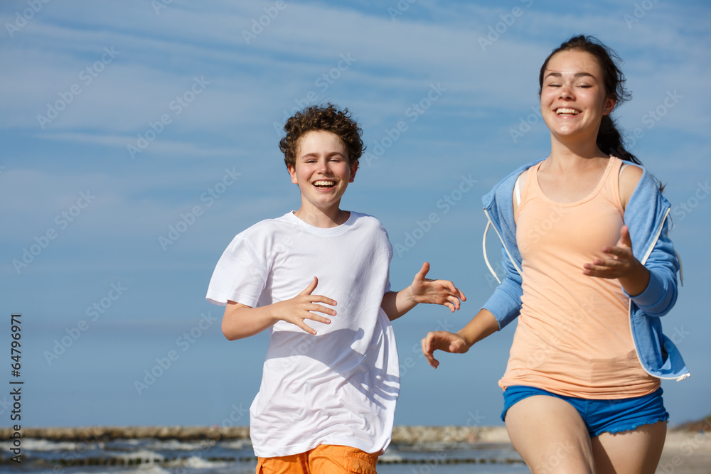 Teenage girl and boy running, jumping on beach Teenage girl and boy running, jumping on beach