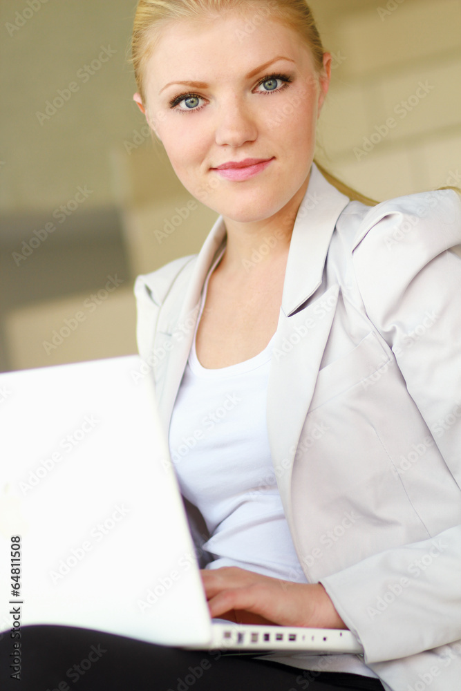Young woman with laptop sitting on the ladder Young woman with laptop sitting on the ladder