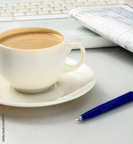 cup of coffee near the laptop and newspapers