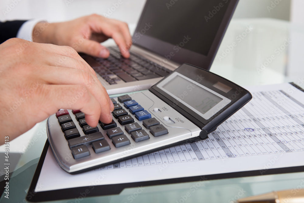 Businessman Calculating Expense In Office Businessman Calculating Expense In Office