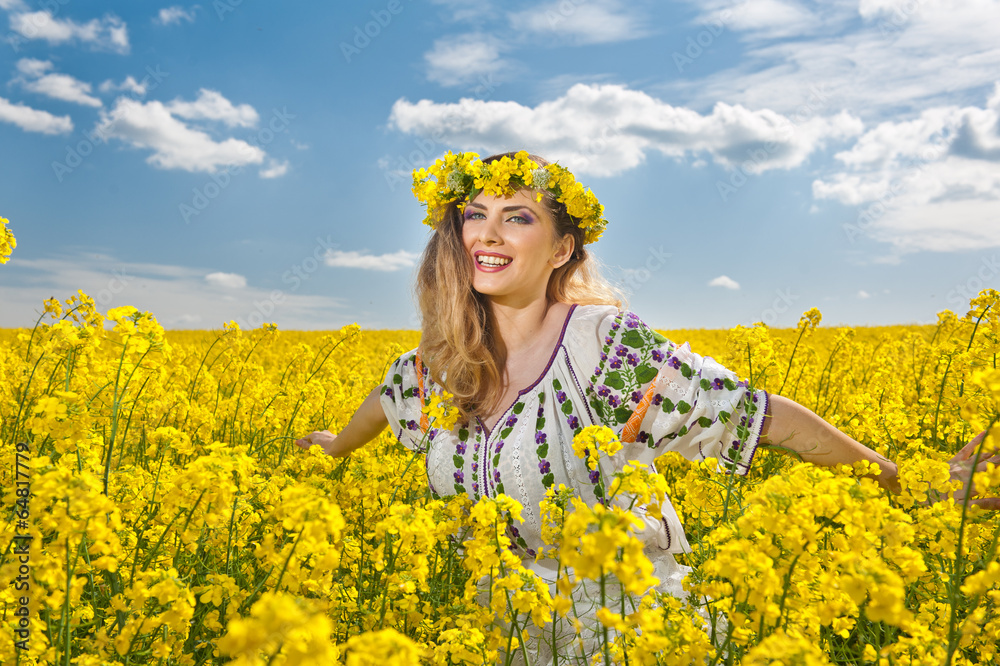 Fototapeta premium Young girl wearing Romanian traditional blouse posing in canola 