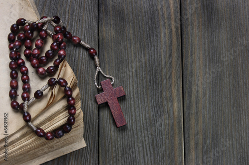Rosary and old book on wooden table