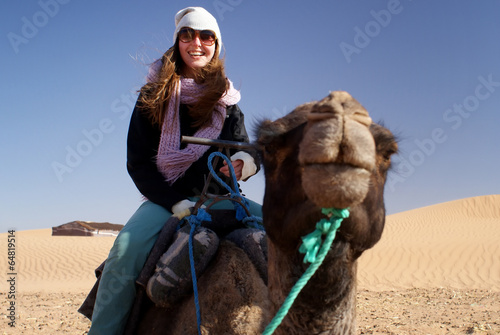 Young woman in desert riding a camel