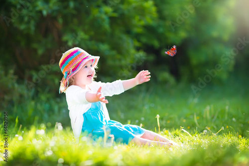 Photography Pretty toddler girl playing with butterfly in garden