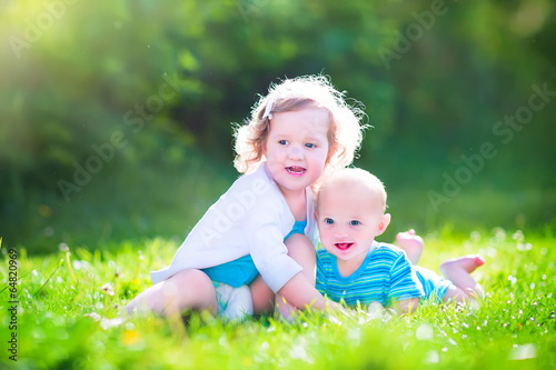 Baby brother and toddler sister in a garden