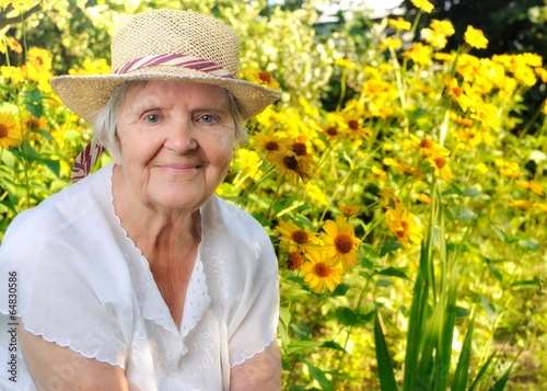 Senior woman in garden full of flowers.