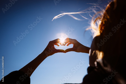 Fototapeta Naklejka Na Ścianę i Meble -  Hands making love shape sign on bright blue sky.