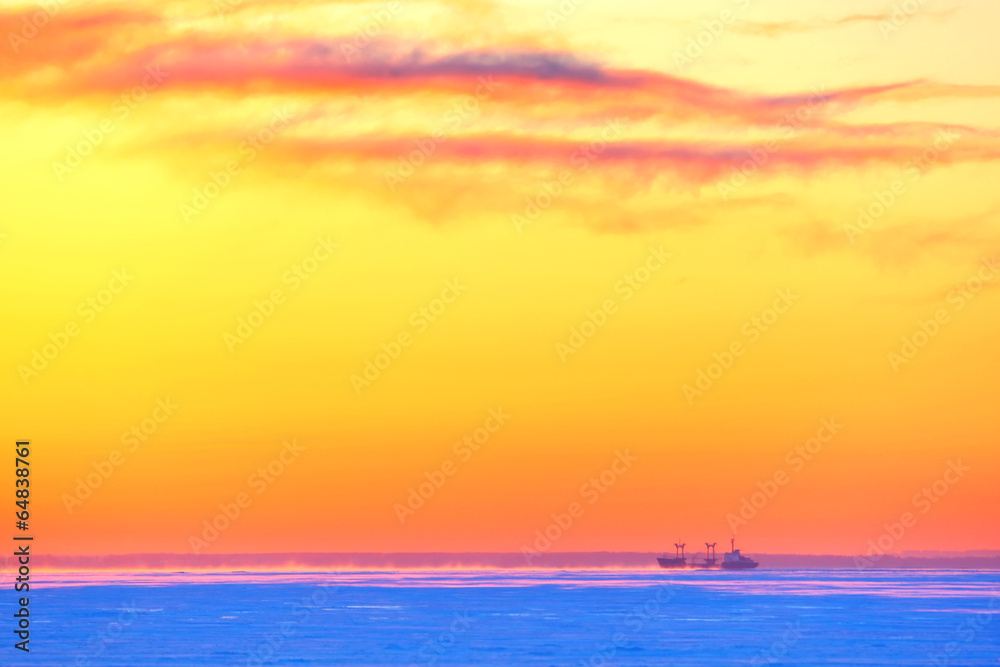 The tanker in ice-rinks at sunset in the winter