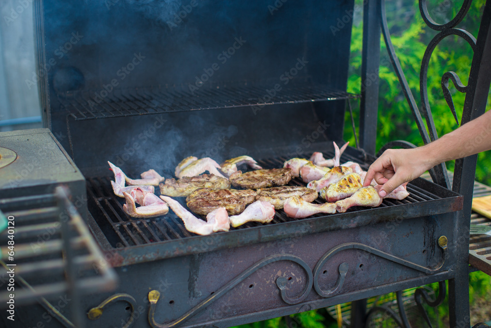 Grilled steak and chiken cooking on an open barbecue