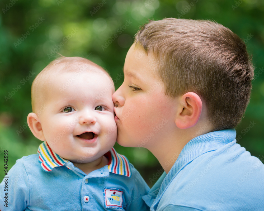 Happy baby boy kissed by his older brother Happy baby boy kissed by his older brother