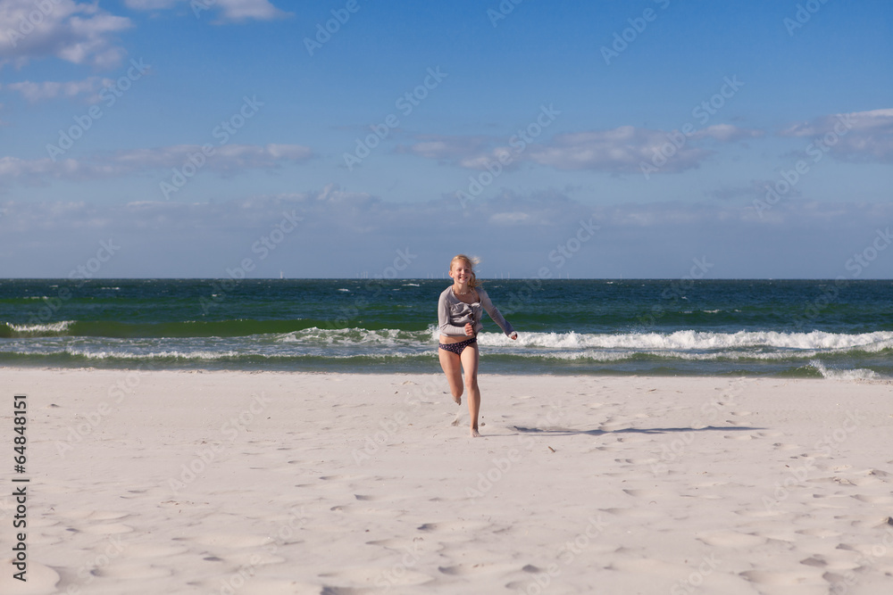 Mädchen rennt barfuß über den Sandstrand