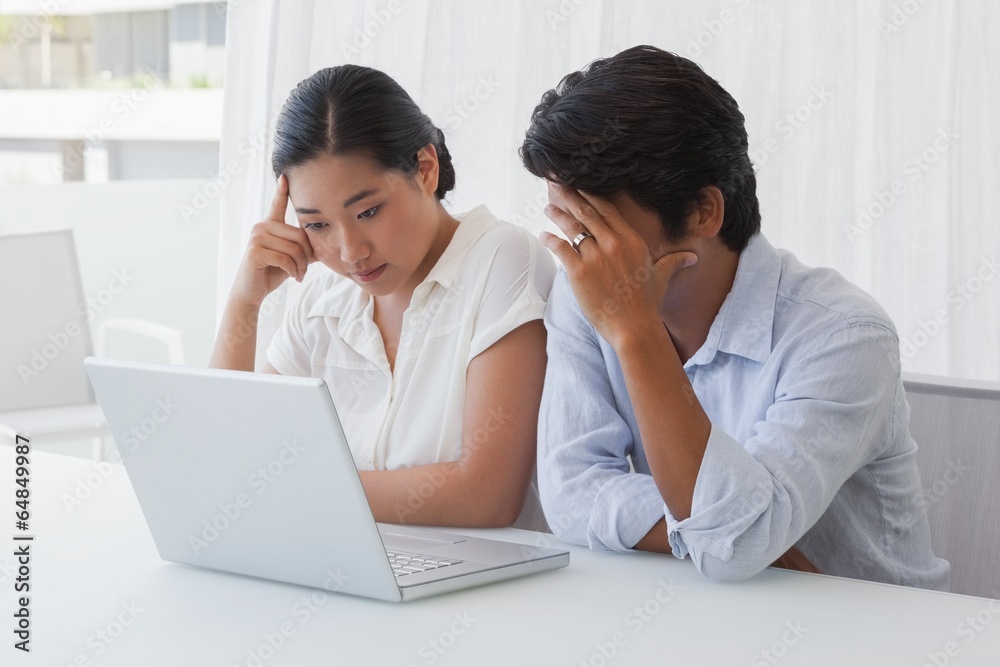 Serious couple using laptop together Serious couple using laptop together