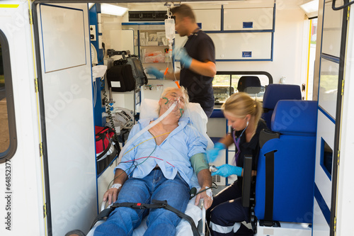 Paramedics treating unconscious man in ambulance photo