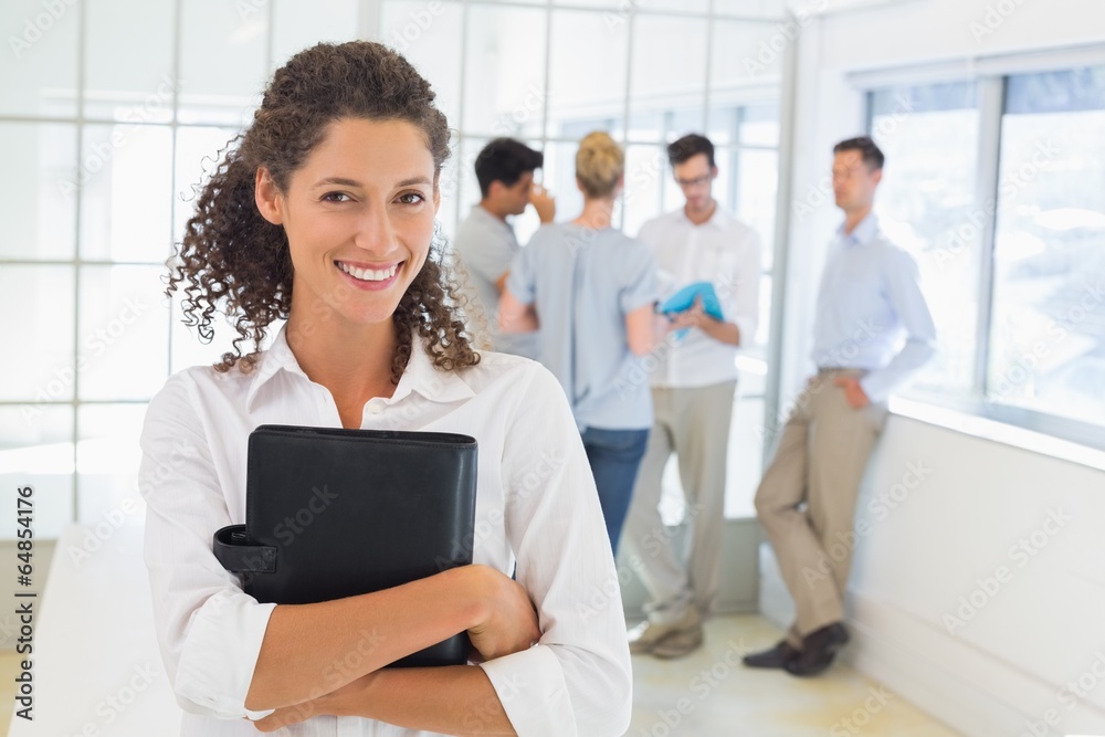 Casual businesswoman smiling at camera holding diary Casual businesswoman smiling at camera holding diary