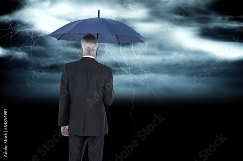 Composite image of businessman holding umbrella © WavebreakmediaMicro