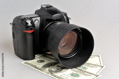 Photo camera with dollars on gray
