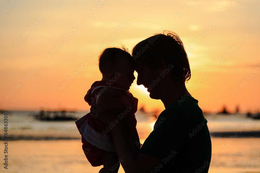 father and little daughter on sunset beach