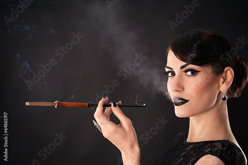 attractive woman with dark makeup smokes a cigarette