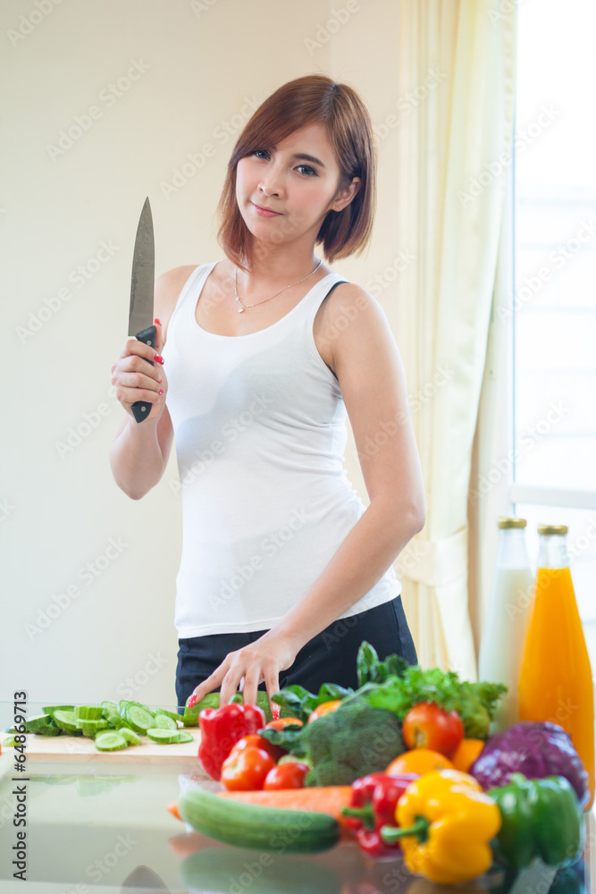Happy woman cooking vegetables green salad