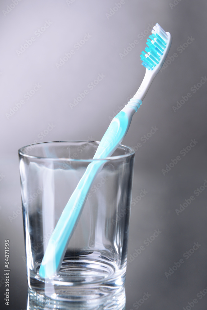Toothbrush in glass on grey background Toothbrush in glass on grey background