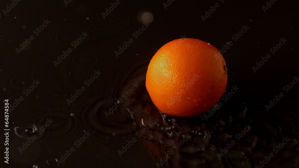 Orange dropping on wet black surface