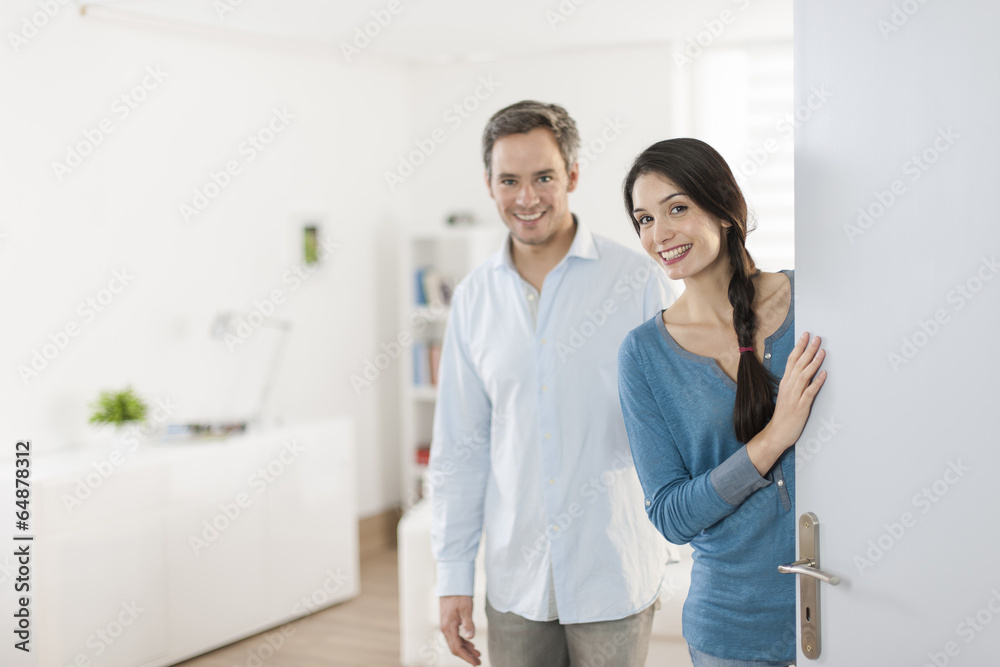 Cheerful couple inviting people to enter in home Cheerful couple inviting people to enter in home