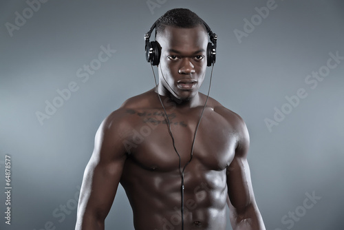 Black african american muscled fitness man with headphones liste