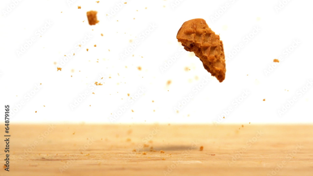 Biscuit falling and breaking on wooden table