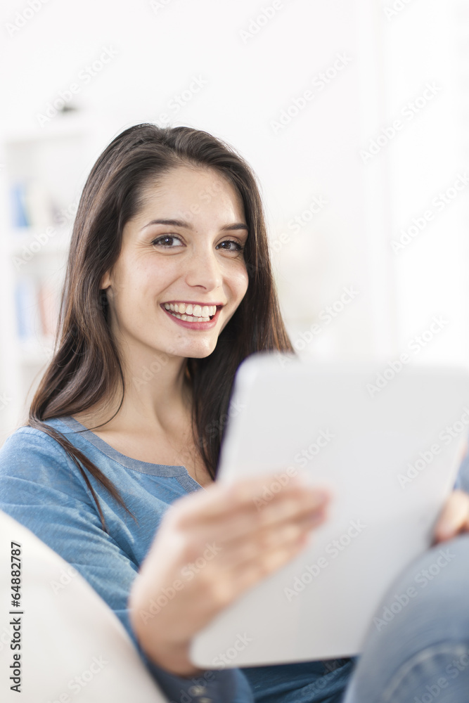 beautiful young woman using digital tablet on a sofa at home