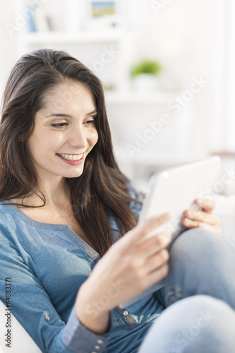 beautiful young woman using digital tablet on a sofa at home