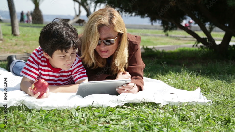 mother and son using digital tablet in park mother and son using digital tablet in park