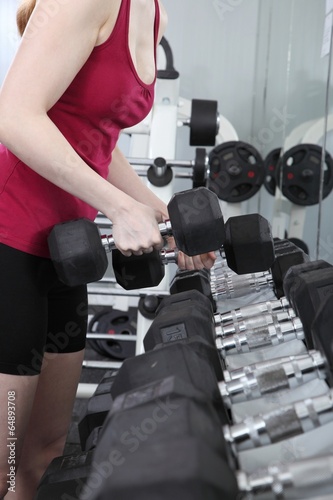 Junge Frau trainiert im Fitnessstudio mit Hanteln