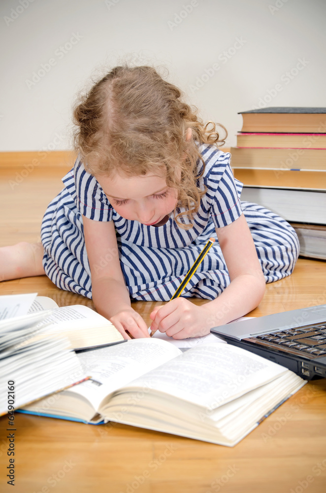 Smart little girl writes diploma at home. Smart little girl writes diploma at home.