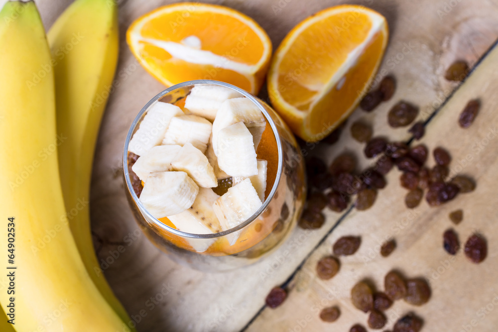 Glass of mixed fresh fruits and raisins with the wholes bananas