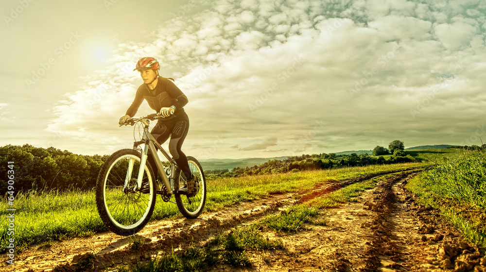 Sport bike woman on a meadow with a beautiful landscape - obrazy, fototapety, plakaty 