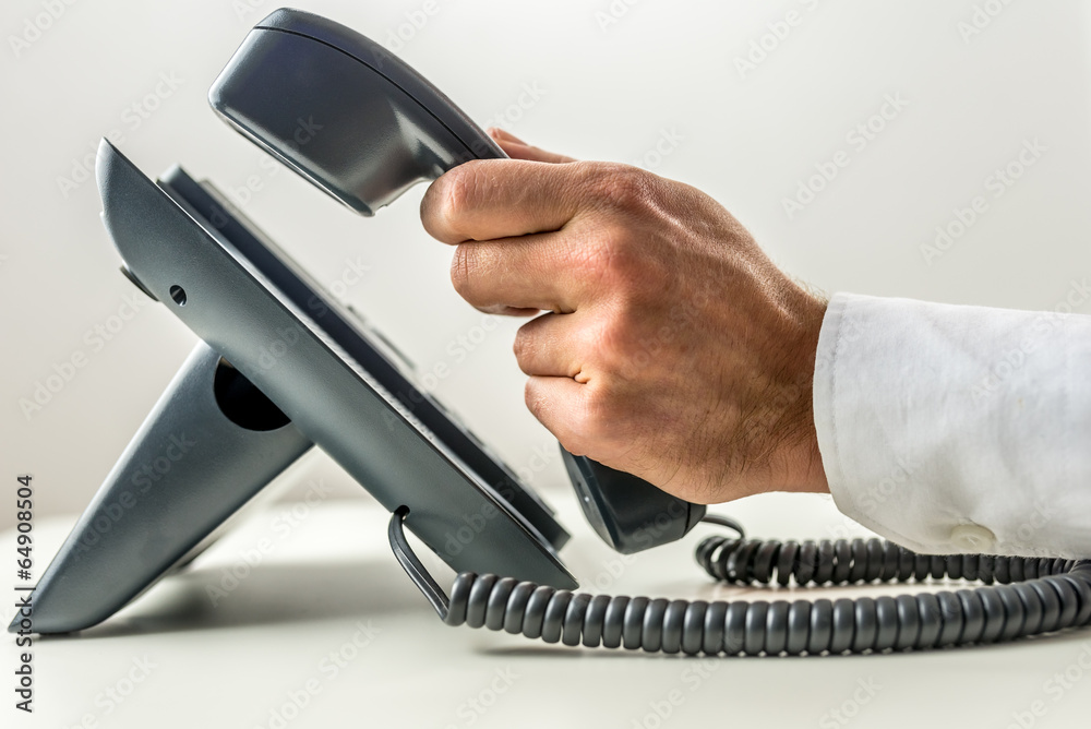 Male hand picking up the receiver of a telephone